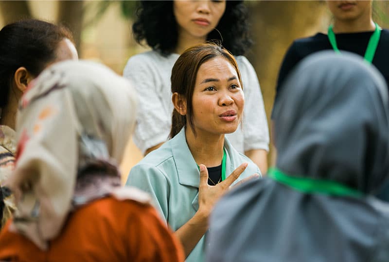 A woman with her hand on her heart talks to a group of women