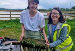 Carly and Anna hold a tray of seagrass