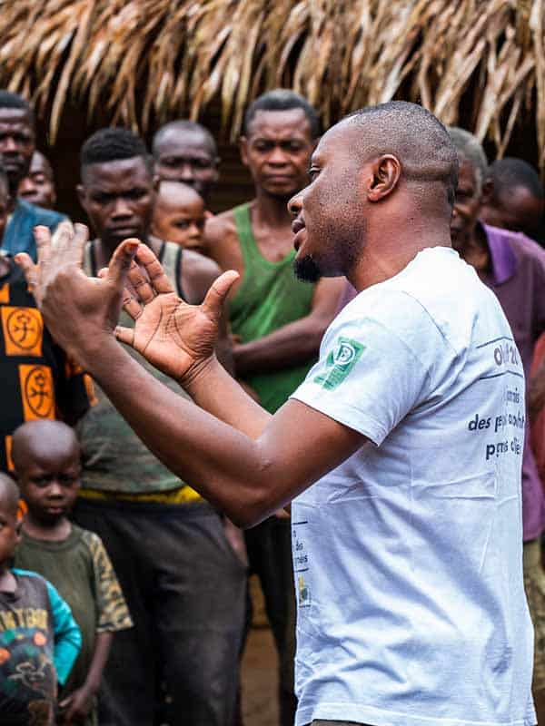 A man explaining something to a group of people, including children