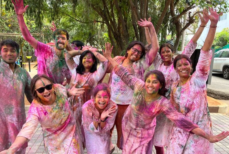 A group of happy people with their arms out in joy covered in pink pigment