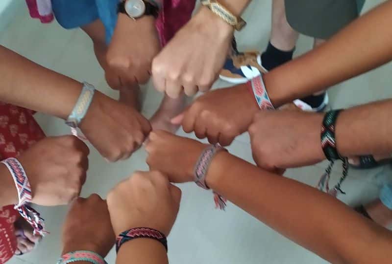 Several hands brought together in the centre of a circle